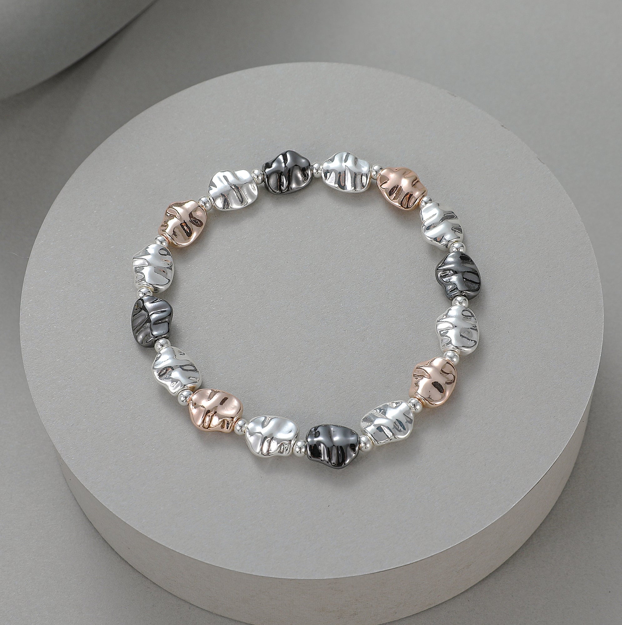 Elasticated bracelet with matte silver, shiny silver, rose and pewter battered circular stations