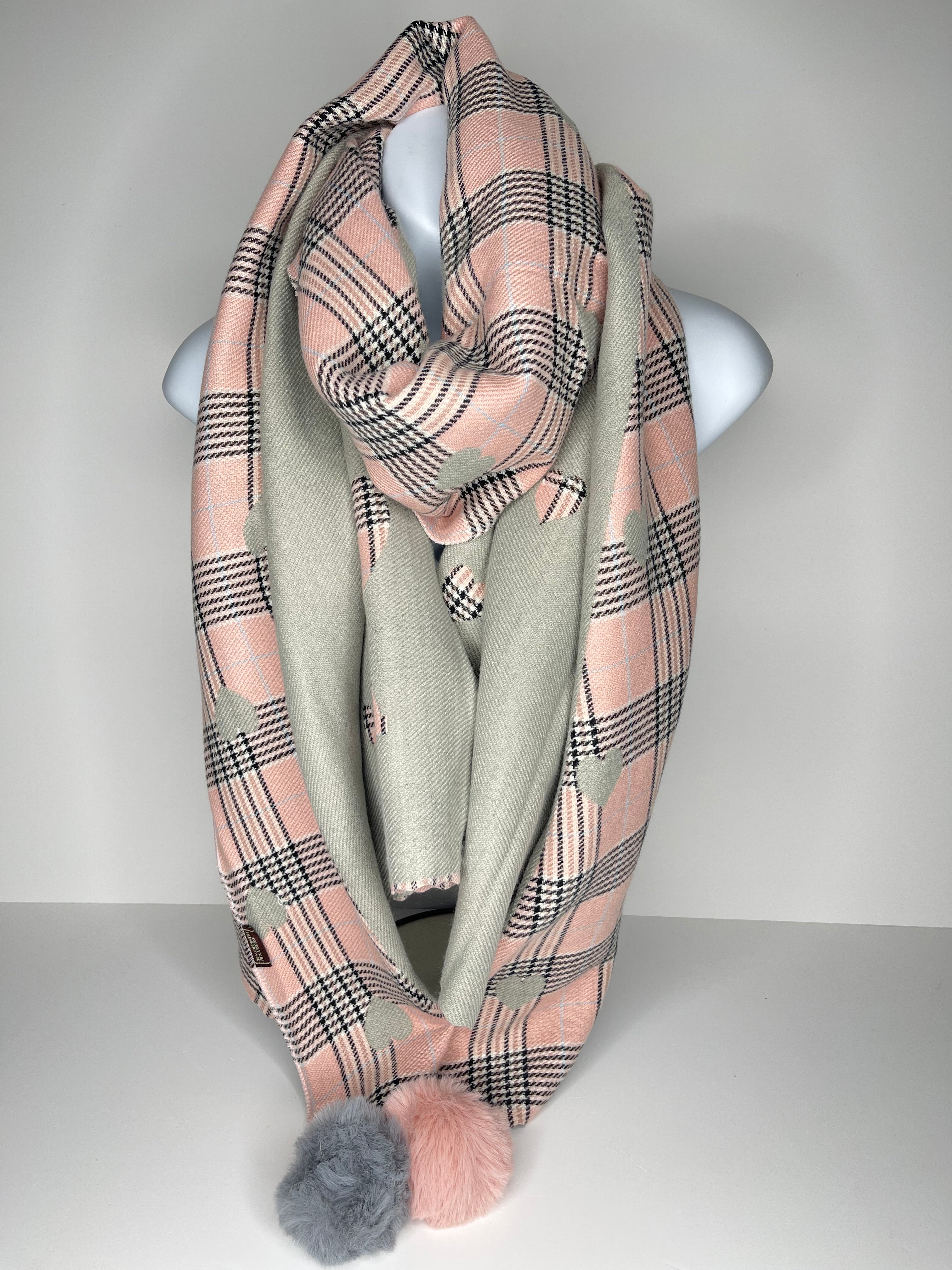Winter weight, cashmere-mix, reversible checkered heart print scarf in shades of light grey, light pink and black, with faux pom-ends