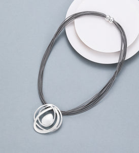 Short necklace, with silver circular spiral pendant and magnetic opening/closure  - on leather strands