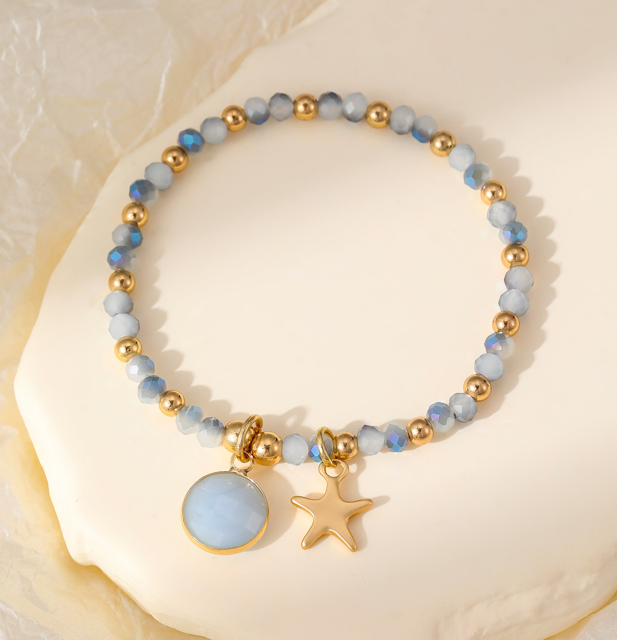 Elasticated bracelet with silver and gold beads and star & crystal pendant