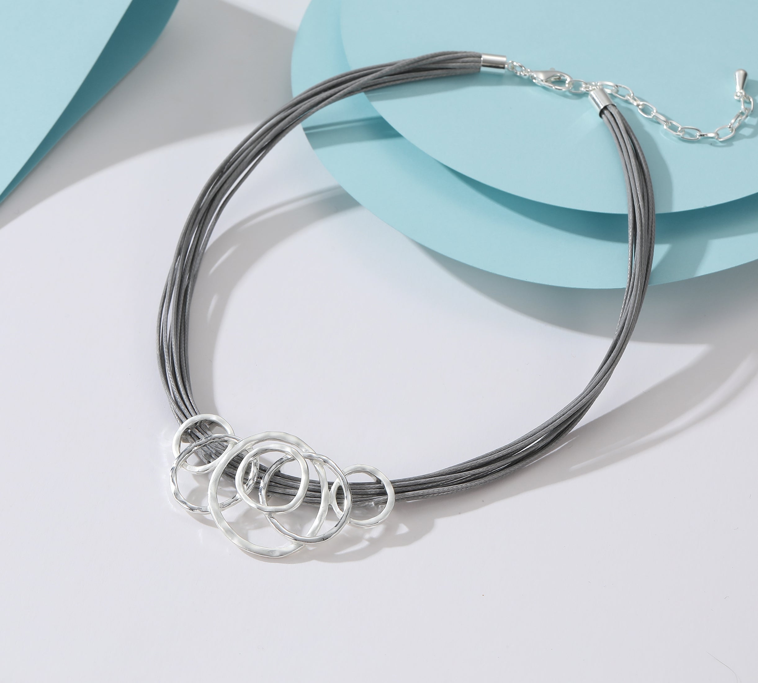 Short necklace, with silver circular inter-linked pendant on grey leather with extension chain